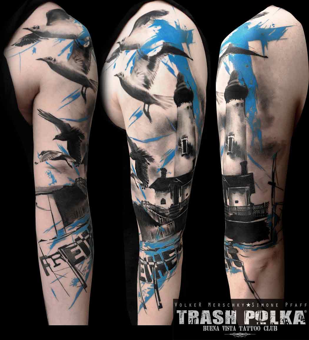 A trash polka arm tattoo shows a lighthouse with seagulls and the word freedom and cross in blue ink