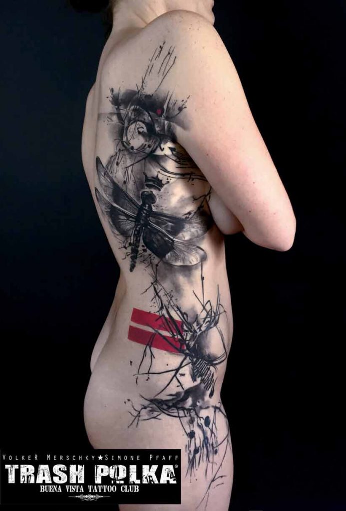 trash polka tattoo on the inside of a woman very graphic with dragonfly and red accents