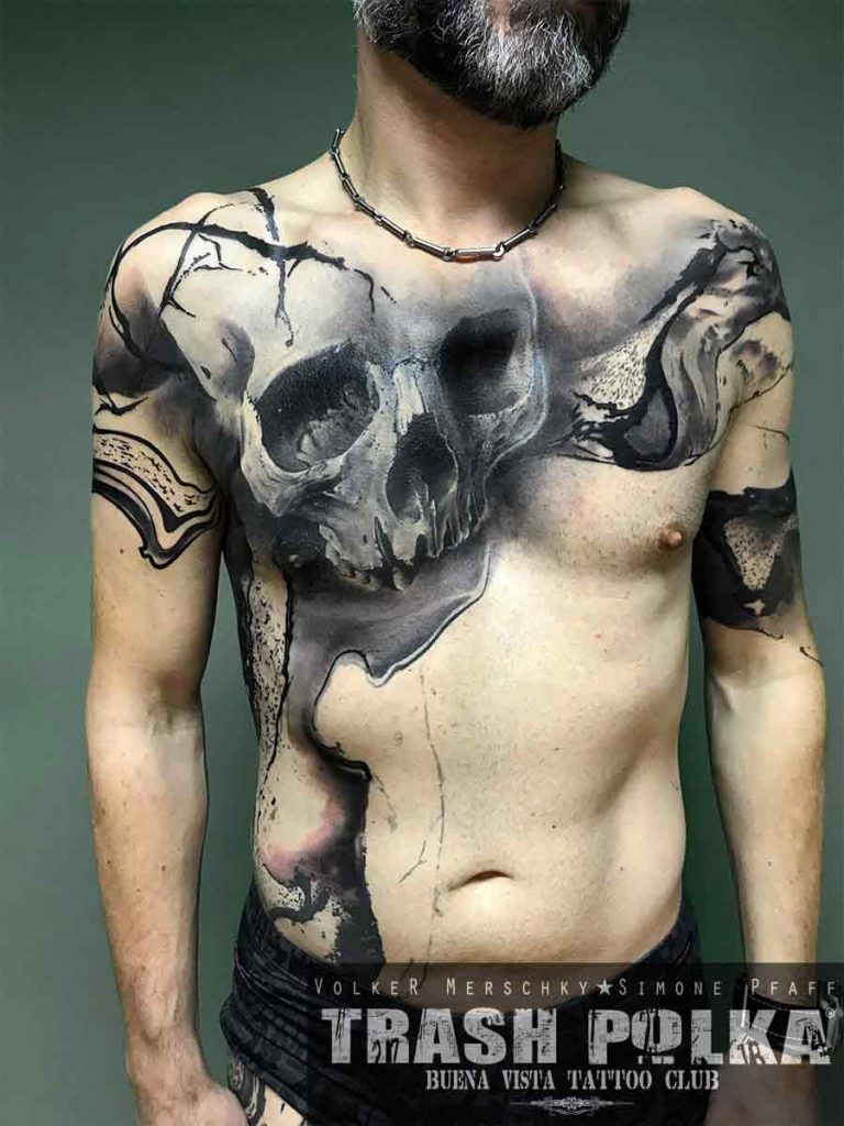 trash polka tattoo of a large skull on the front of a man