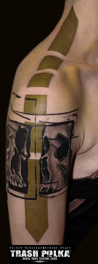 trash polka tattoo on a lady arm two lateral skulls facing each other, separated by a long thick green arrow reaching to the neck